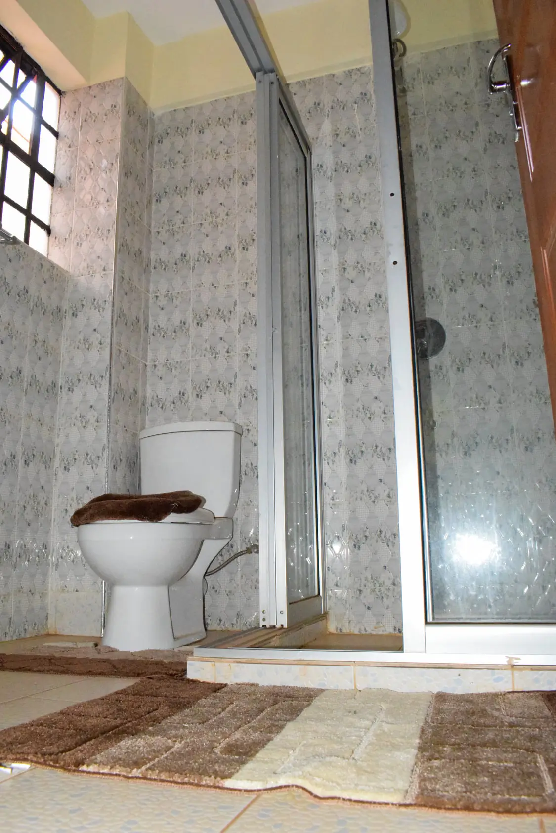 Bathroom with toilet, shower enclosure, patterned walls