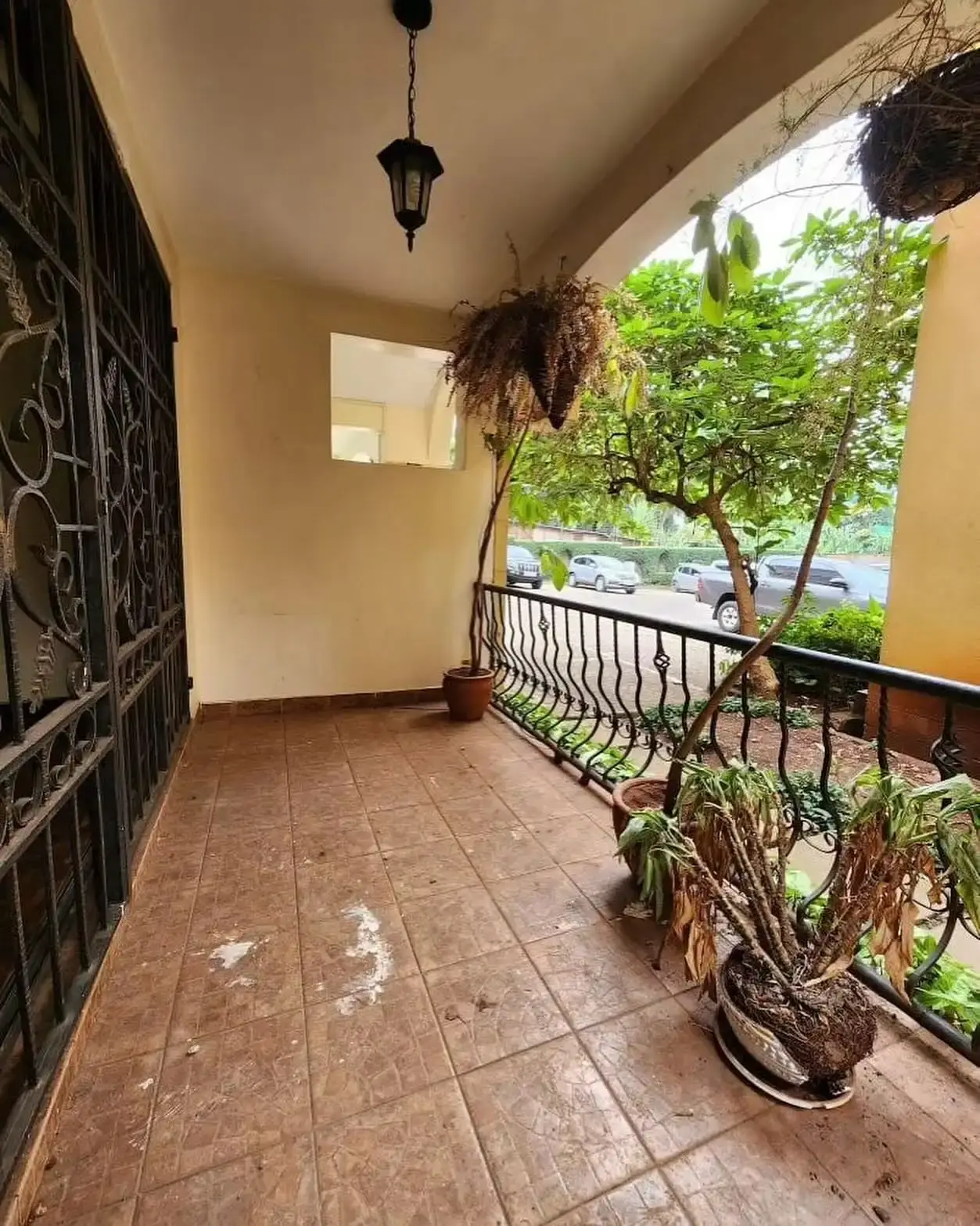 Covered balcony with railing overlooking tree-lined street
