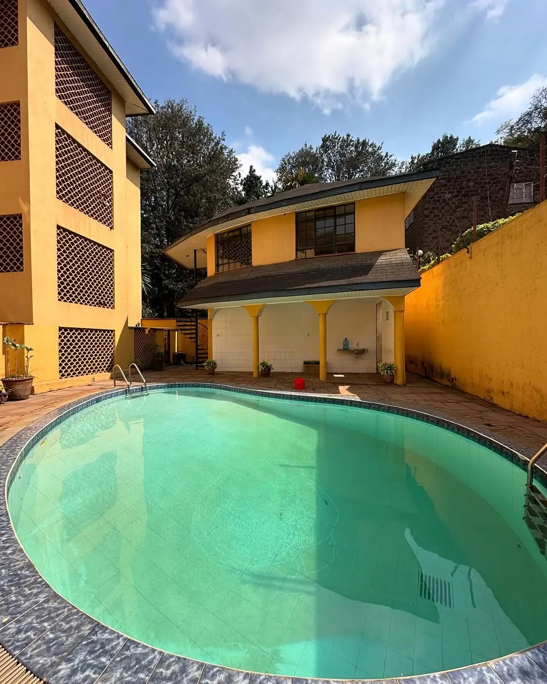 Circular turquoise swimming pool with yellow compound walls