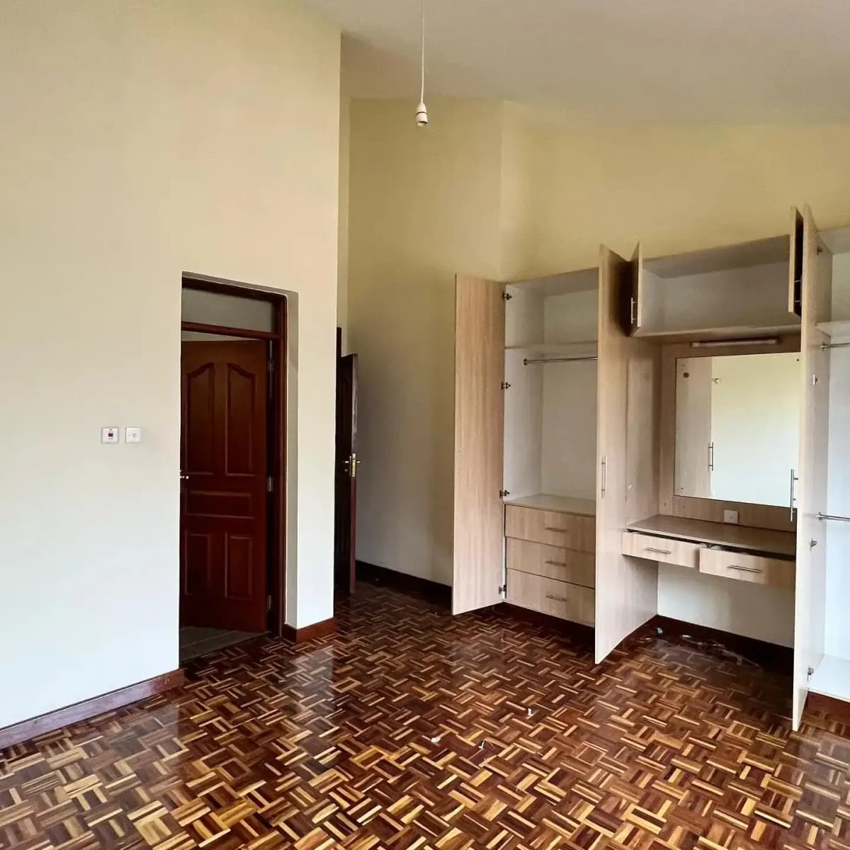 Spacious bedroom with built-in wardrobes and herringbone flooring