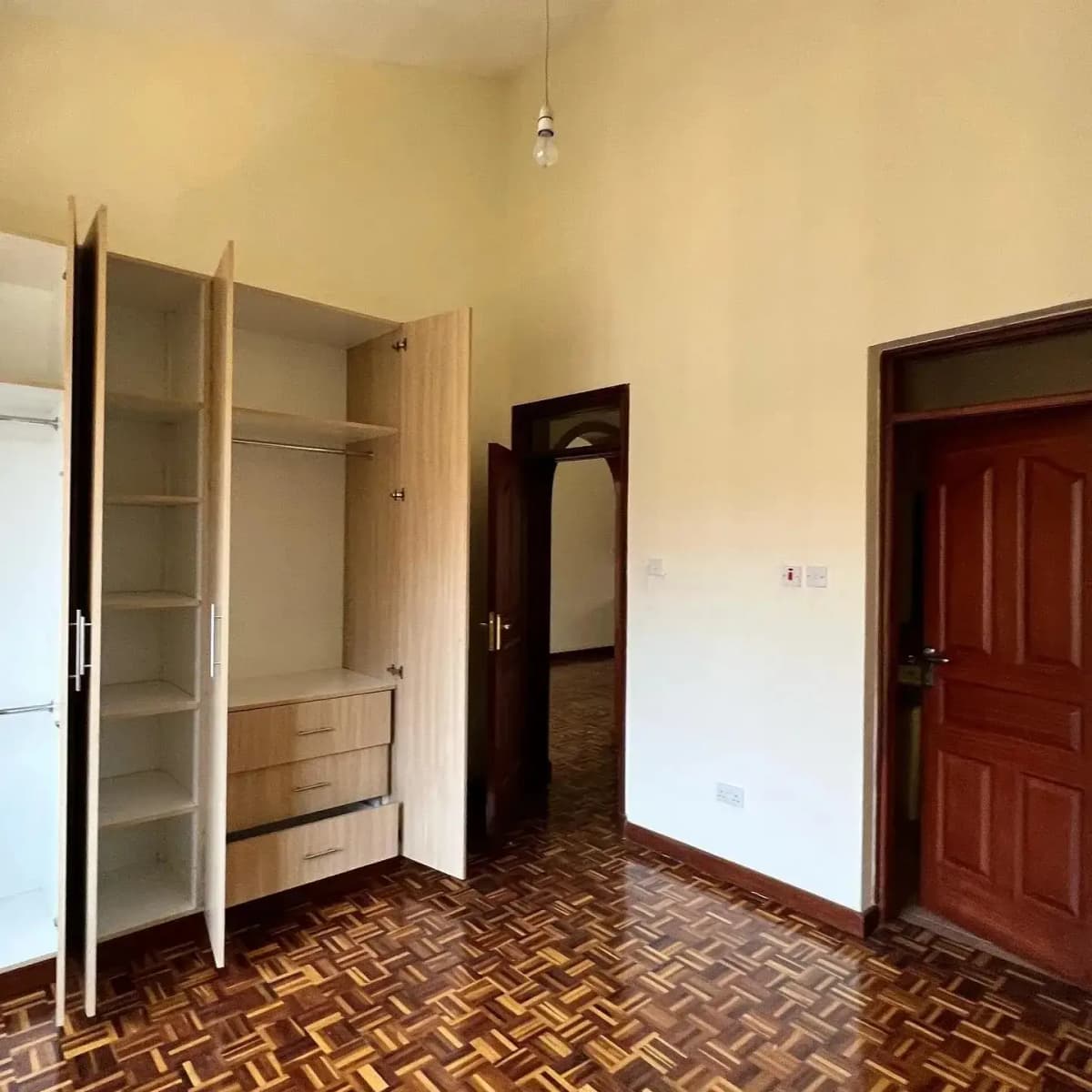 Spacious bedroom with built-in wardrobe and herringbone flooring
