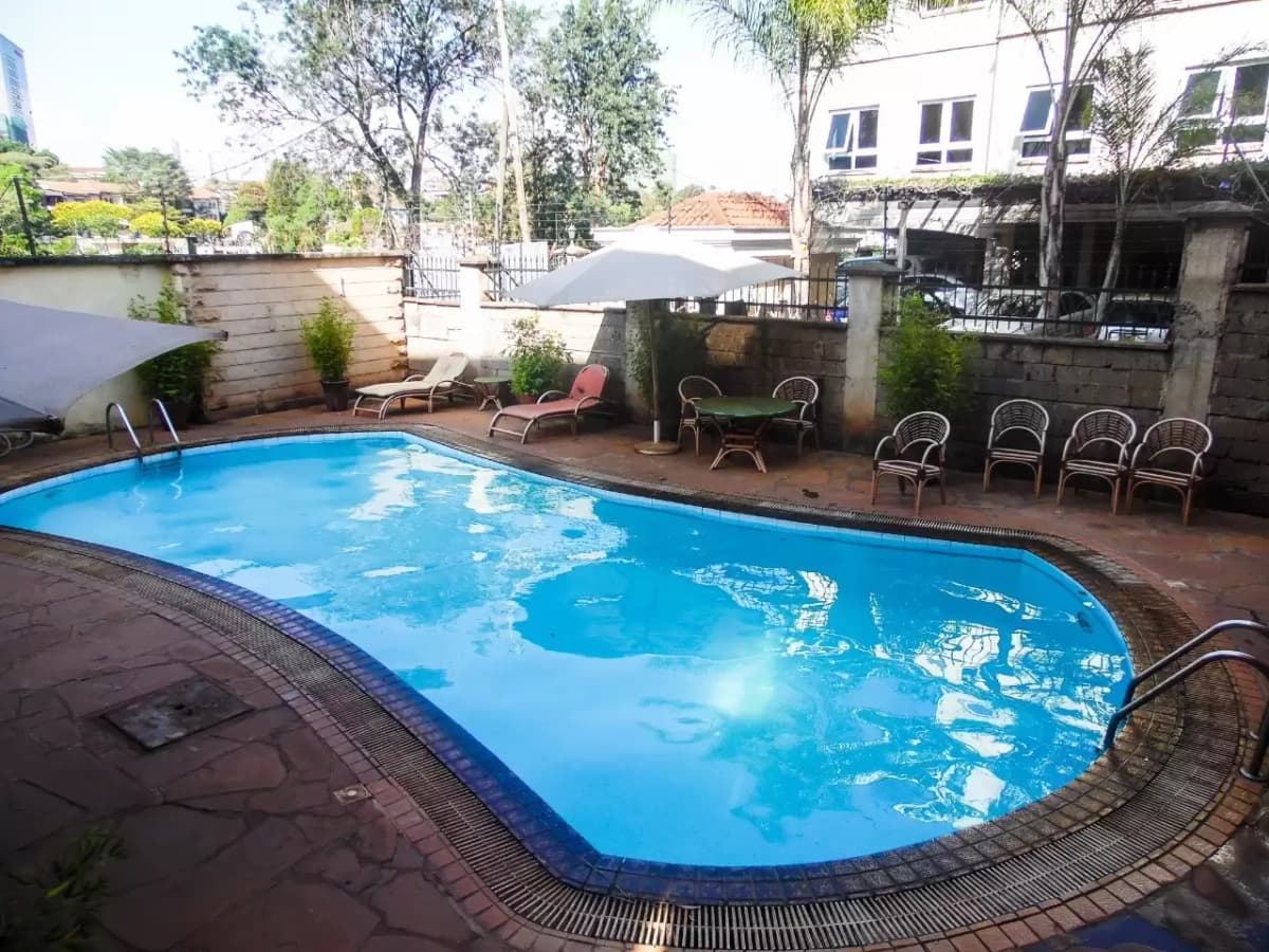 Curved swimming pool with lounging area and surrounding landscaping