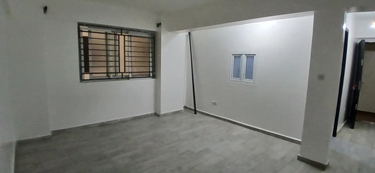 Empty living room with grey concrete floor and barred window