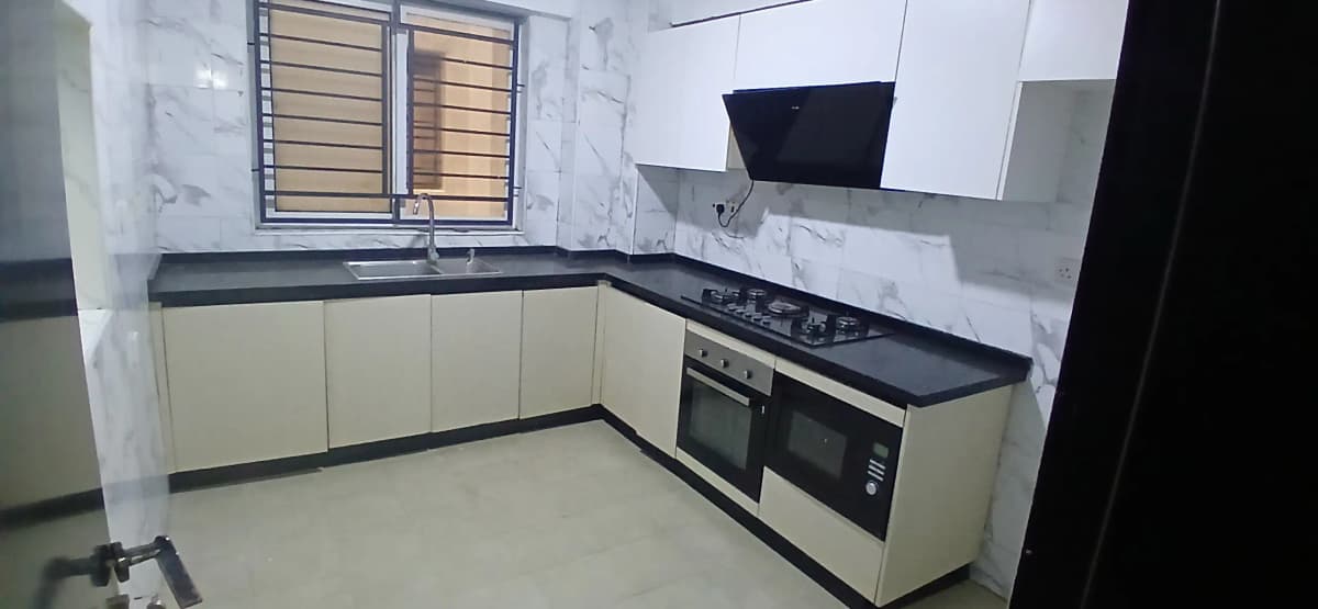 Modern L-shaped kitchen with cream cabinets and black countertops