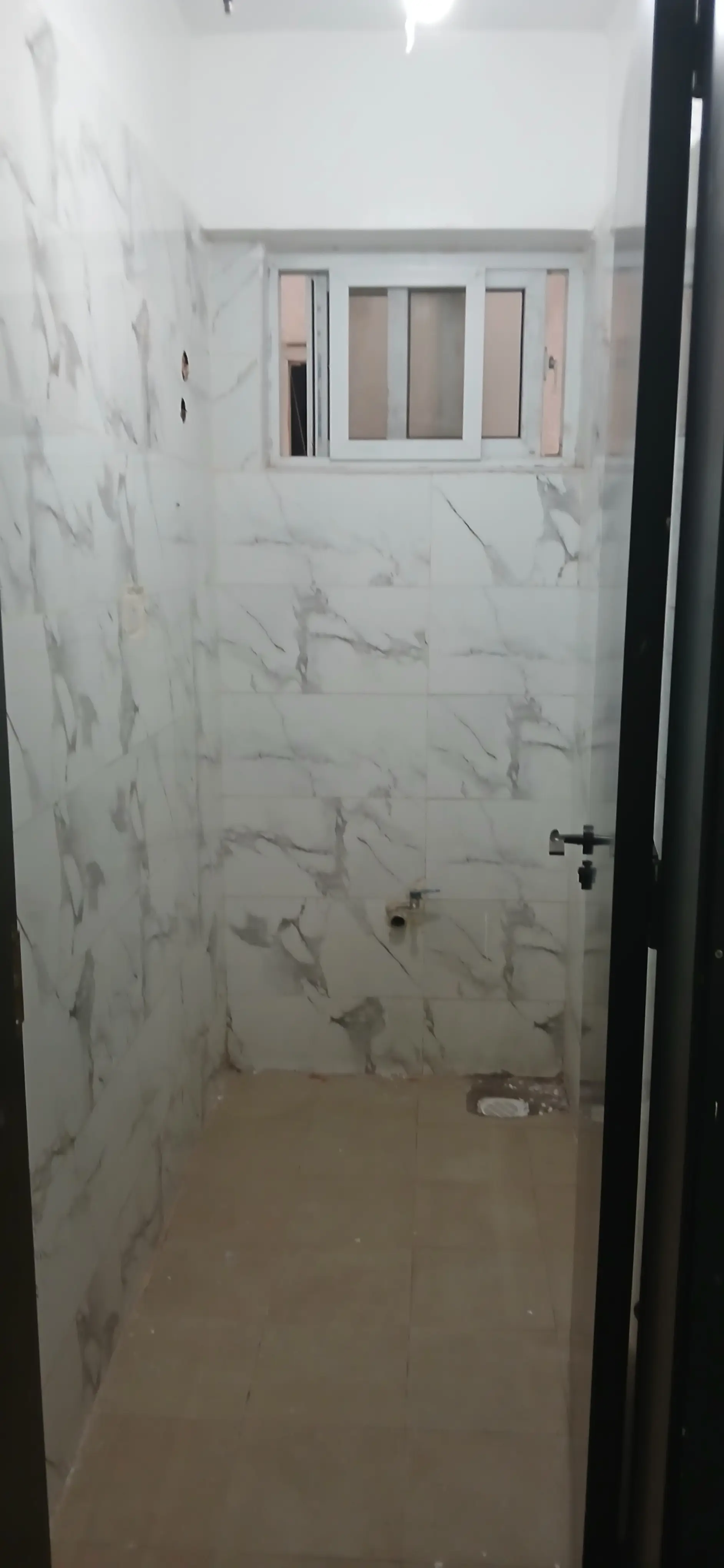 Marble-tiled bathroom with window and dark door frame
