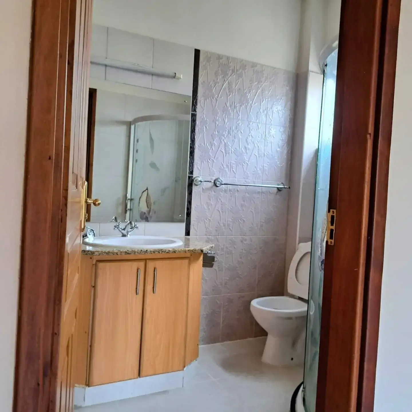 Modern bathroom with wooden vanity, walk-in shower, toilet