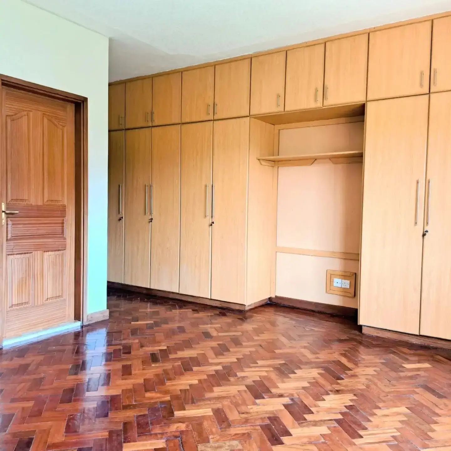 Spacious bedroom with extensive wooden built-in wardrobes