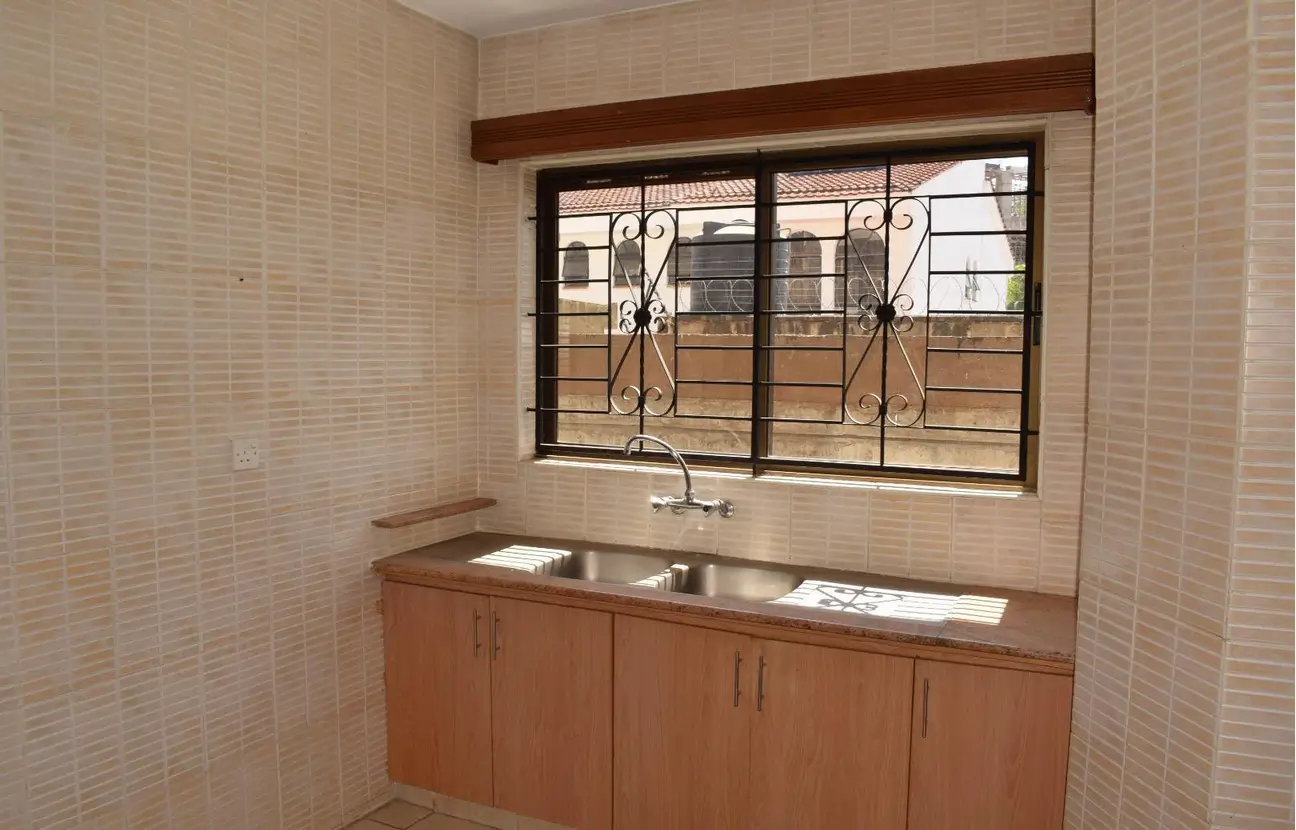 Compact kitchen with double sink and barred window view