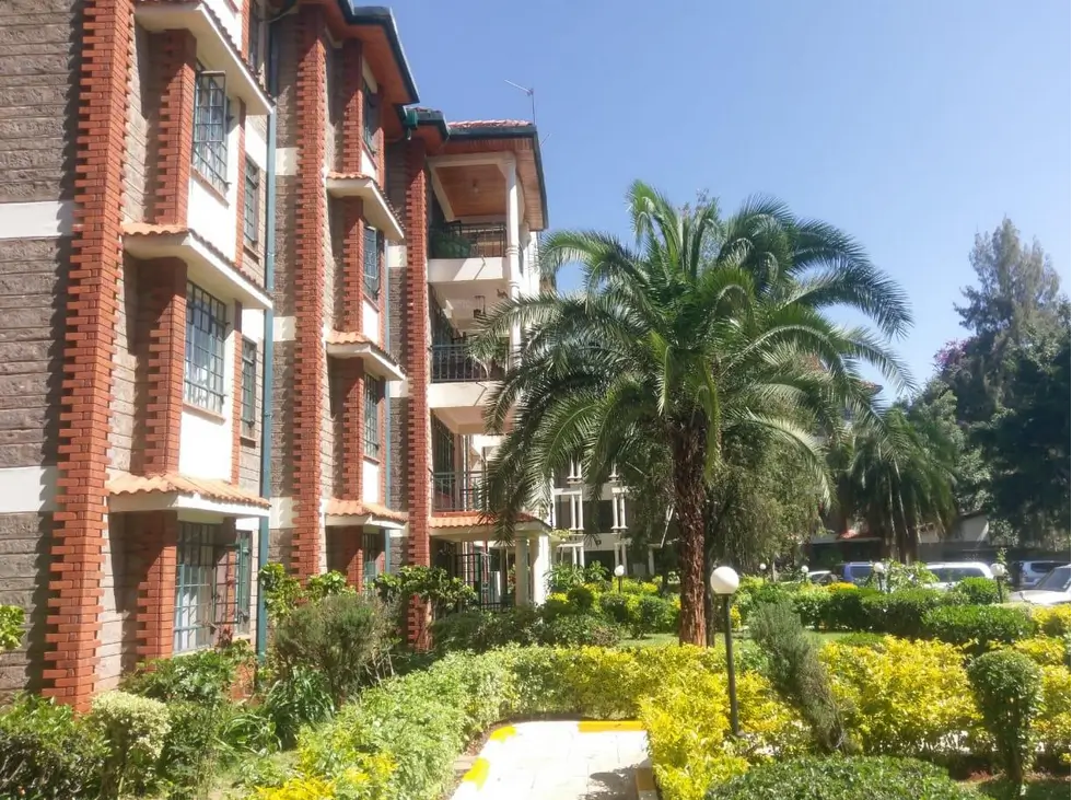 Red brick multi-story apartment building with manicured compound grounds