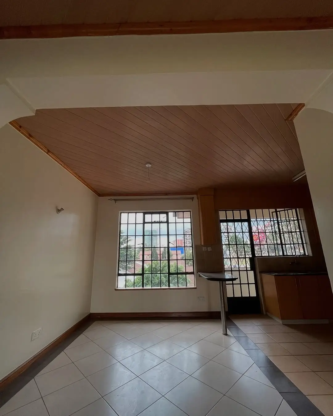 Spacious living room with large barred windows and wooden ceiling