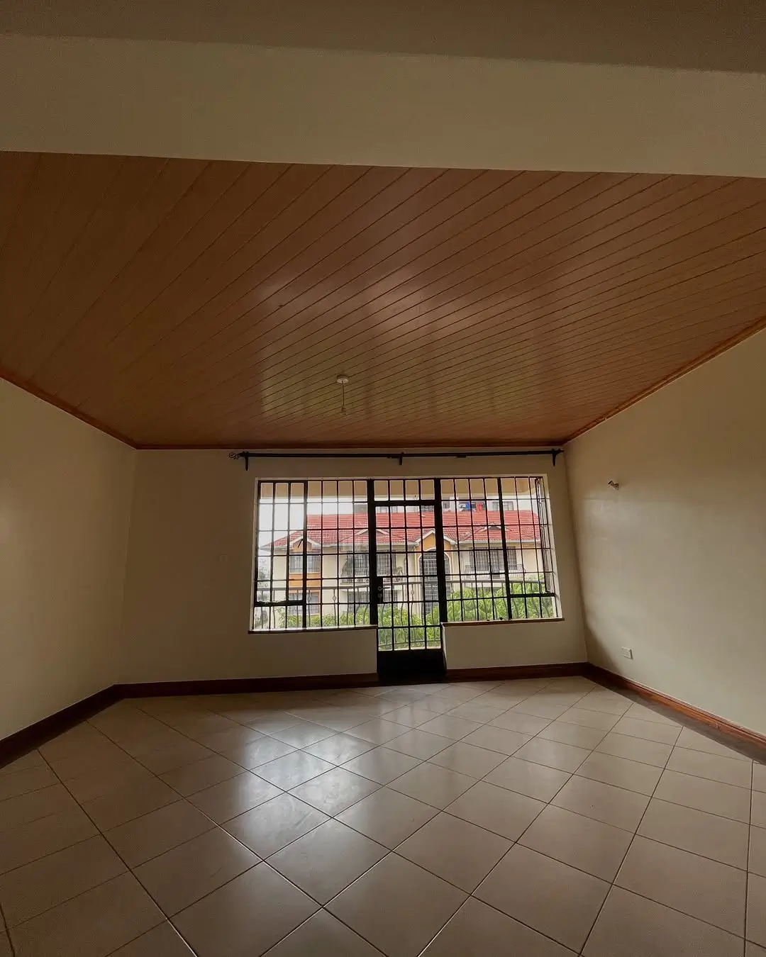 Spacious empty living room with tile flooring and barred windows