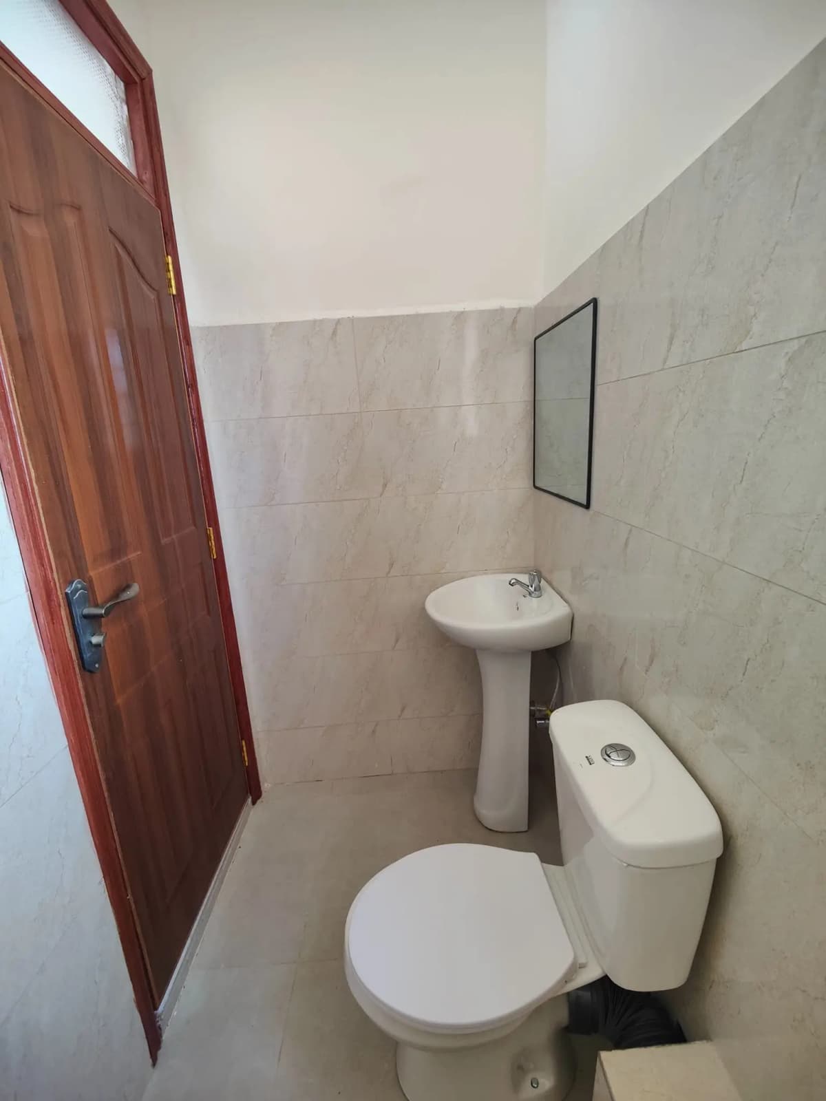 Simple bathroom with pedestal sink, toilet, and tiled walls