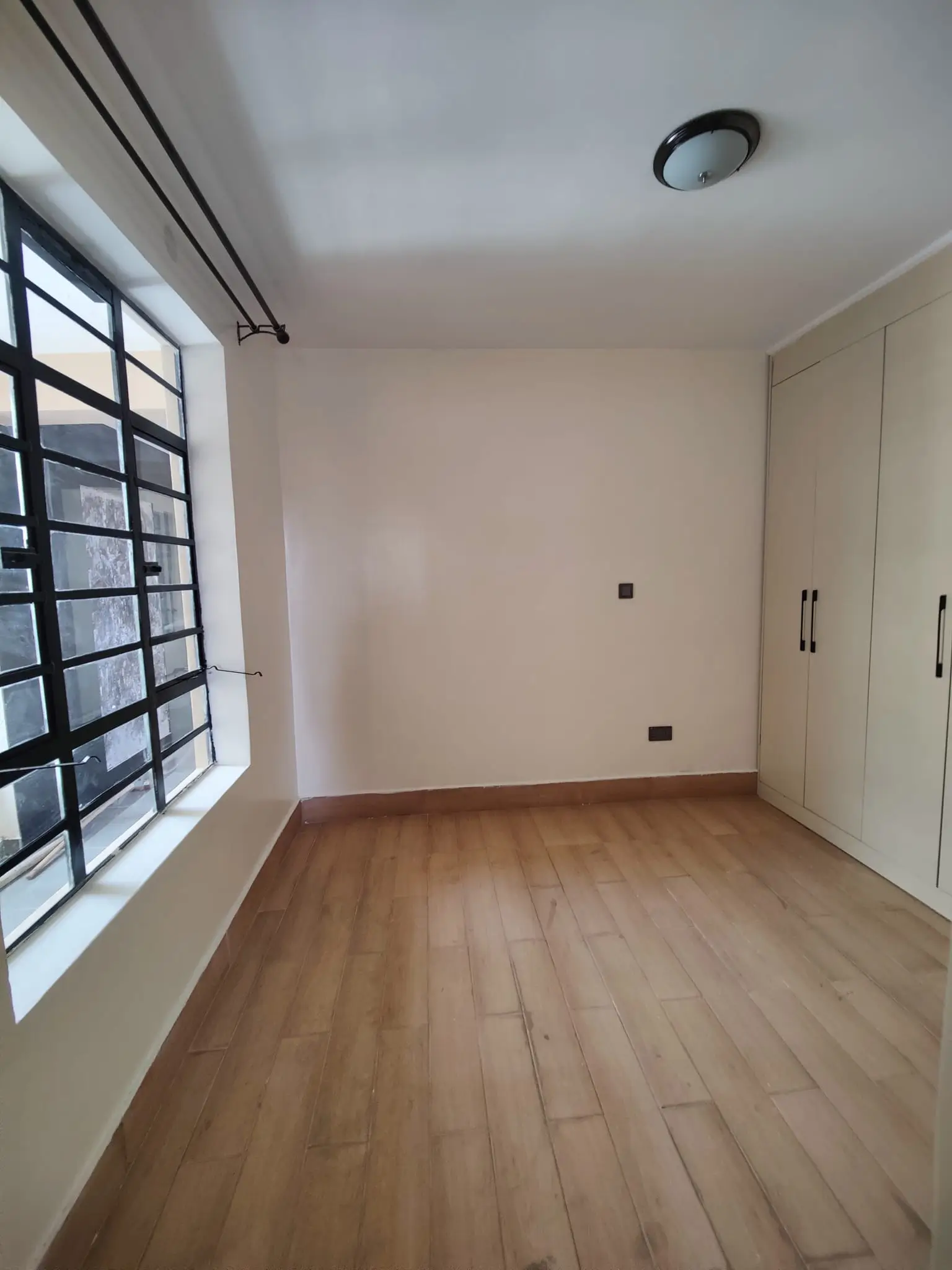 Unfurnished bedroom with wooden flooring and built-in wardrobes