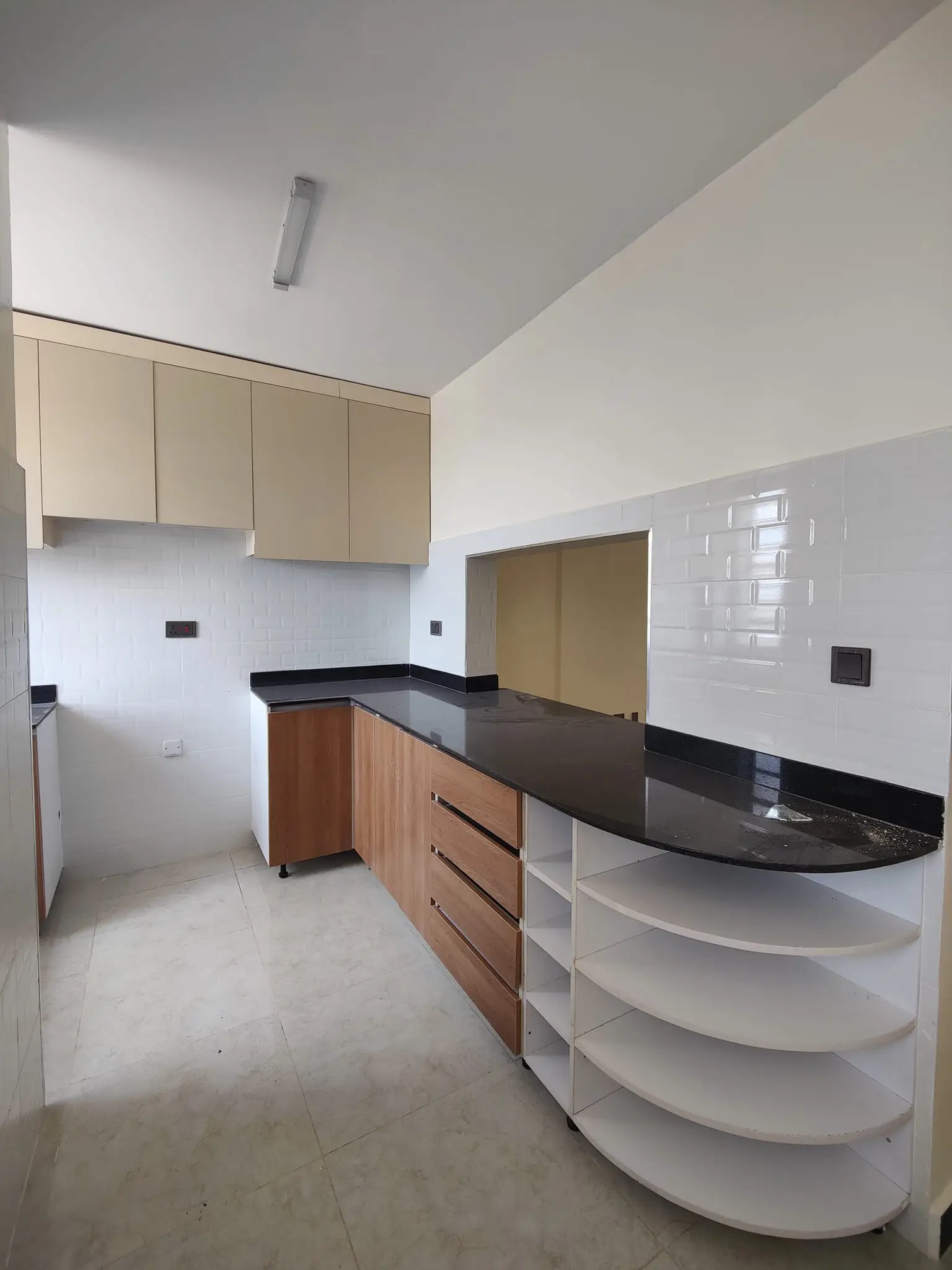 Modern kitchen with curved counter, black countertops, wood cabinets