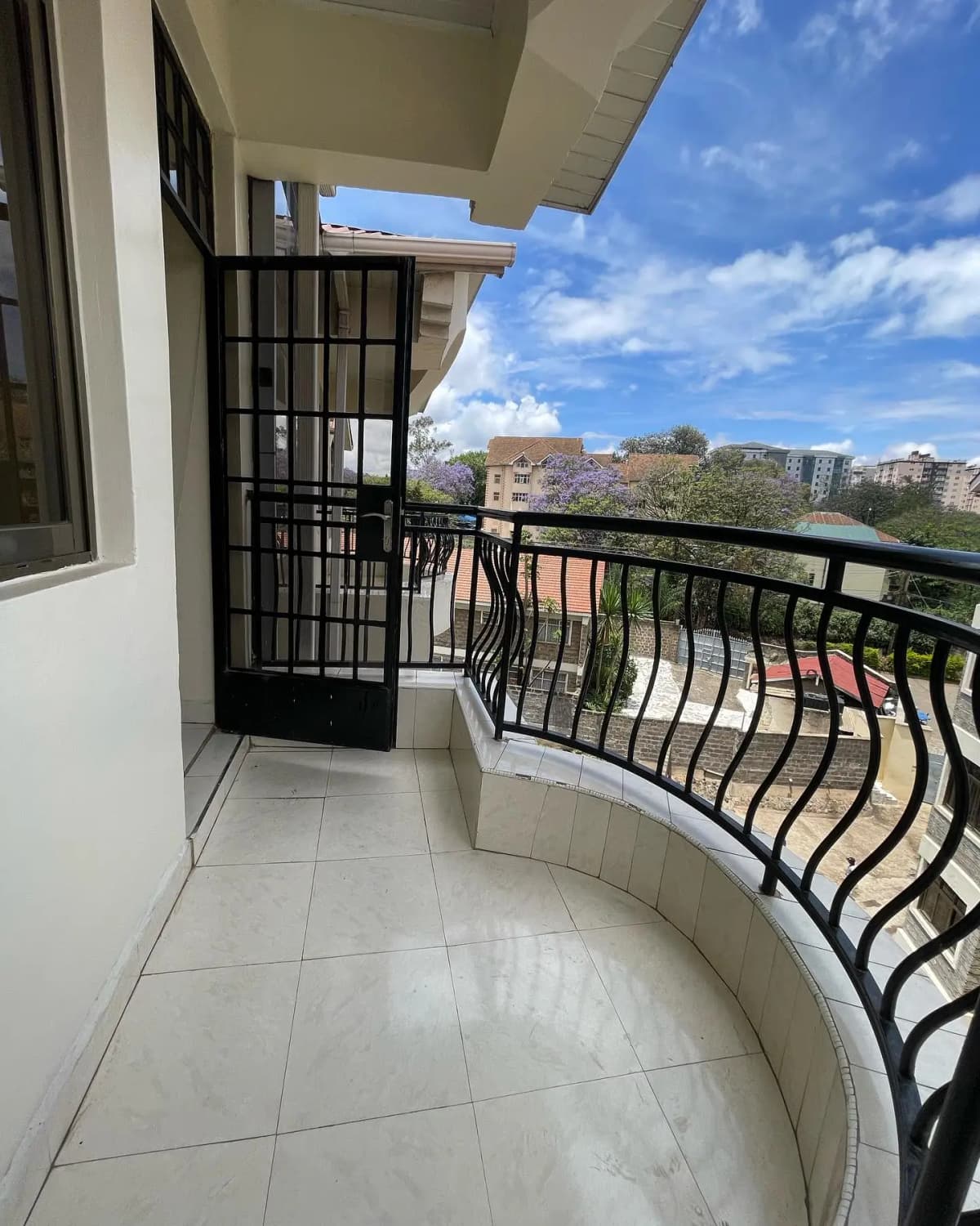 Curved balcony with black railings overlooking residential compound