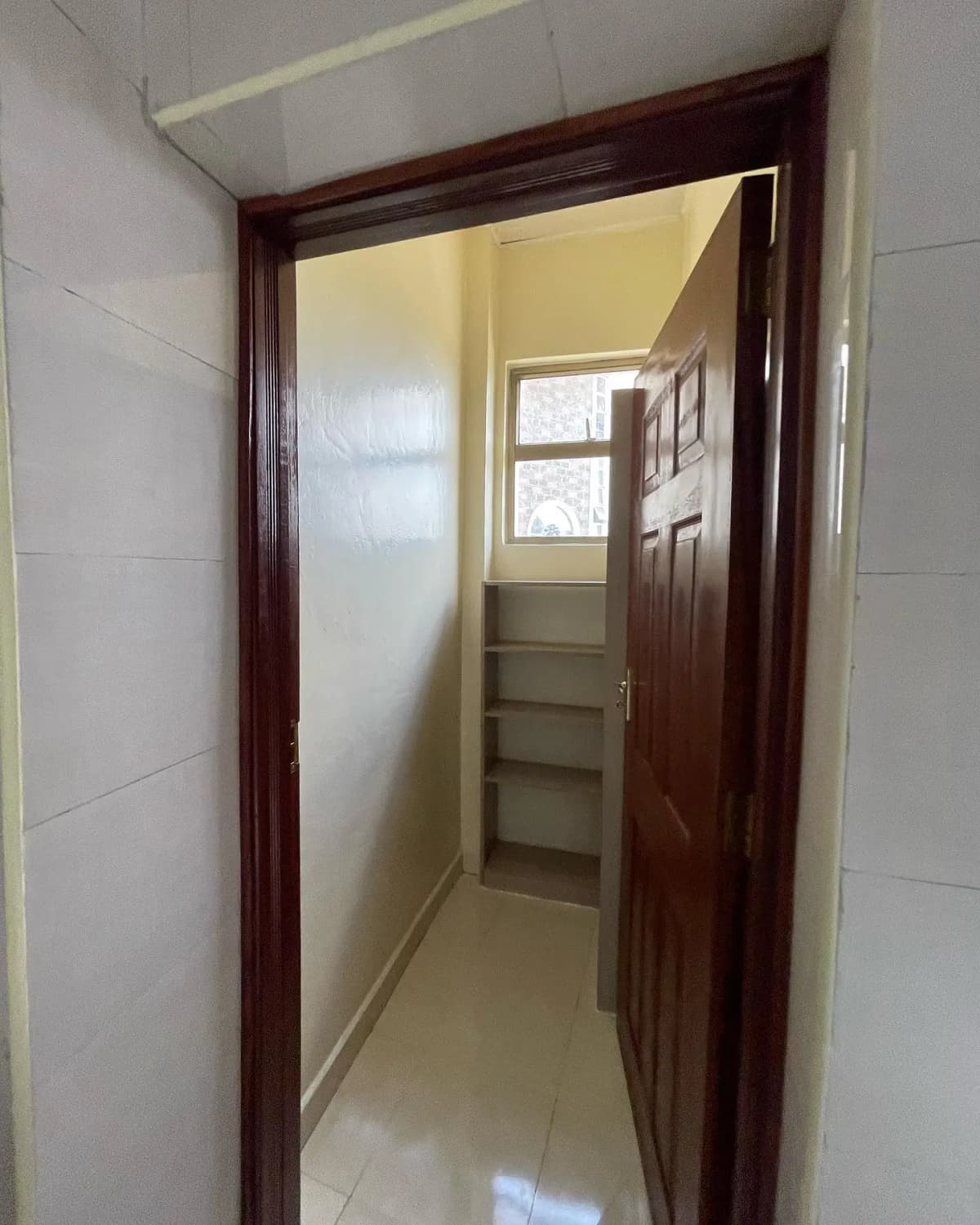 Narrow hallway with dark wood door frame and tiled walls