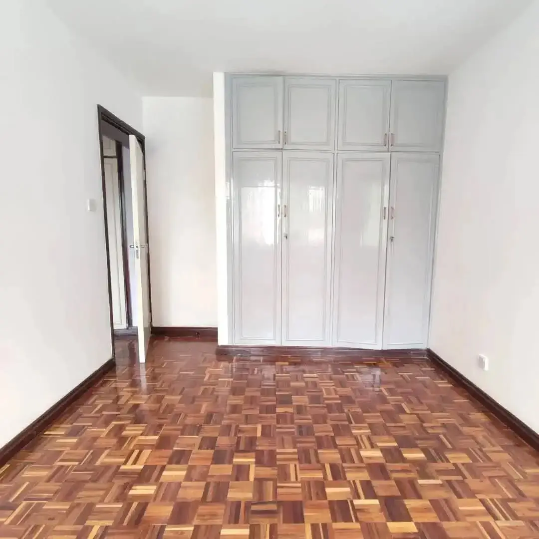 Spacious bedroom with built-in white wardrobes and parquet flooring