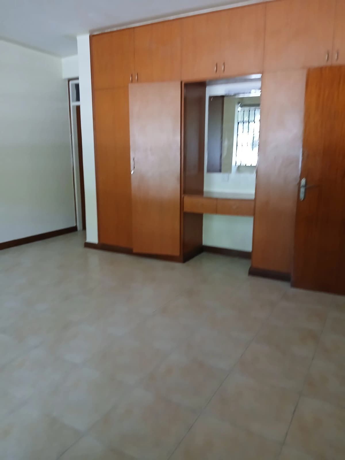 Spacious bedroom with built-in wooden wardrobe and mirror
