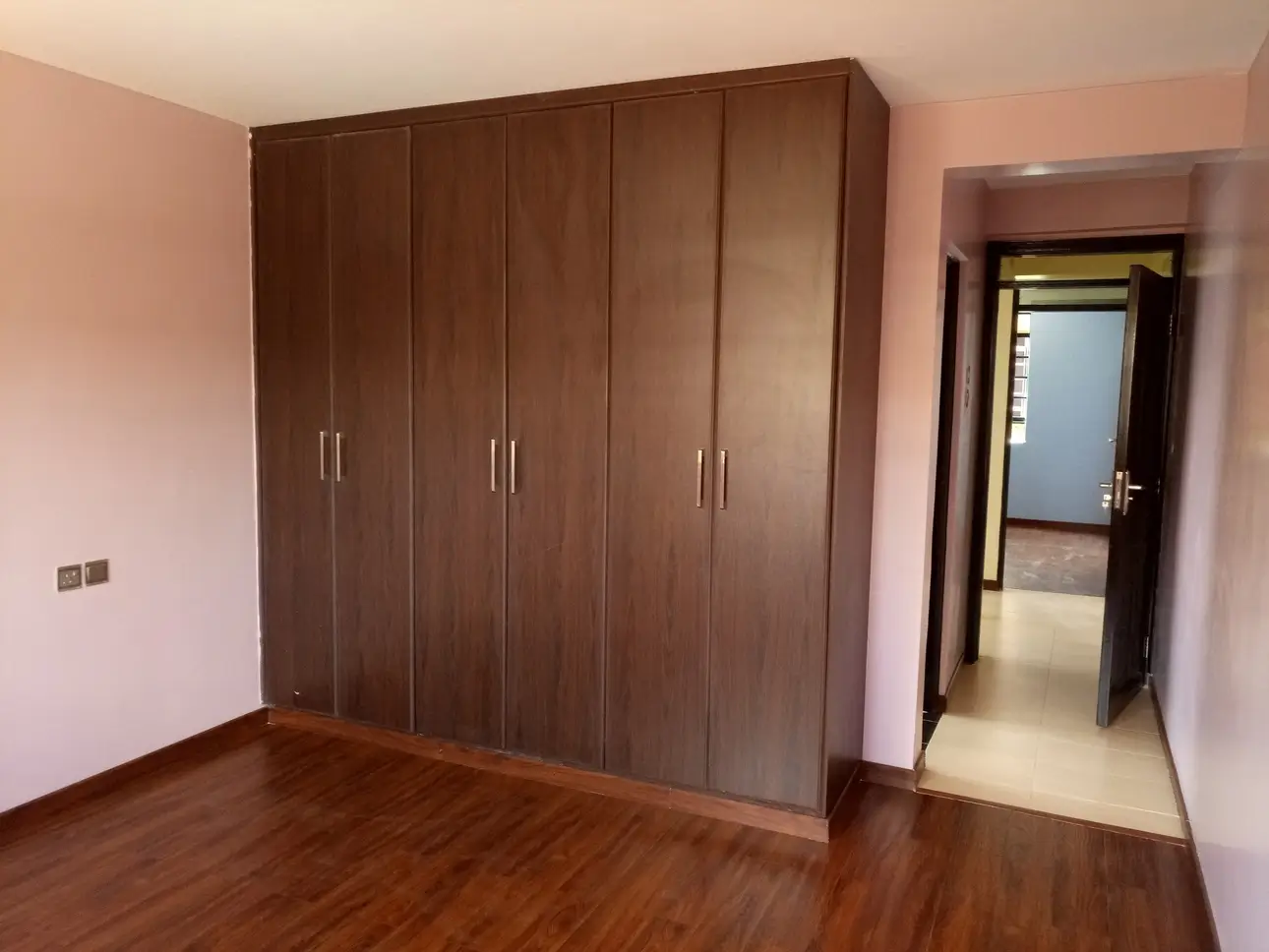 Bedroom with built-in wooden wardrobe and hardwood flooring
