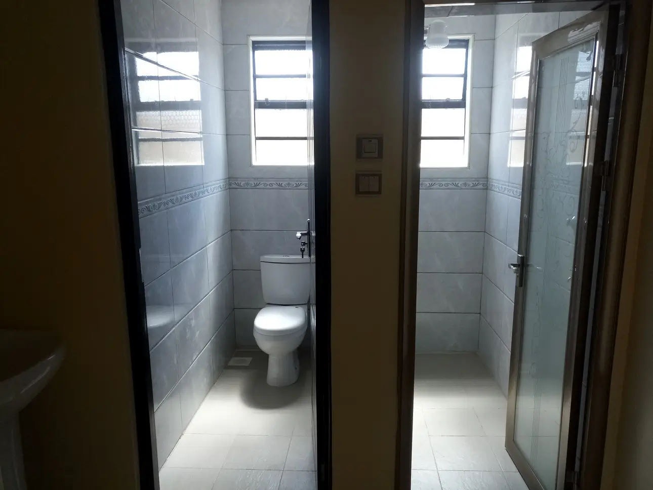 Bright bathroom with toilet, shower enclosure, tiled walls