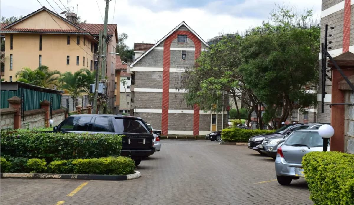 Residential compound parking area with multiple vehicles and hedges
