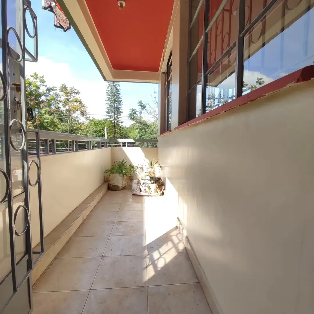 Covered balcony with red awning, tiled floor, garden view