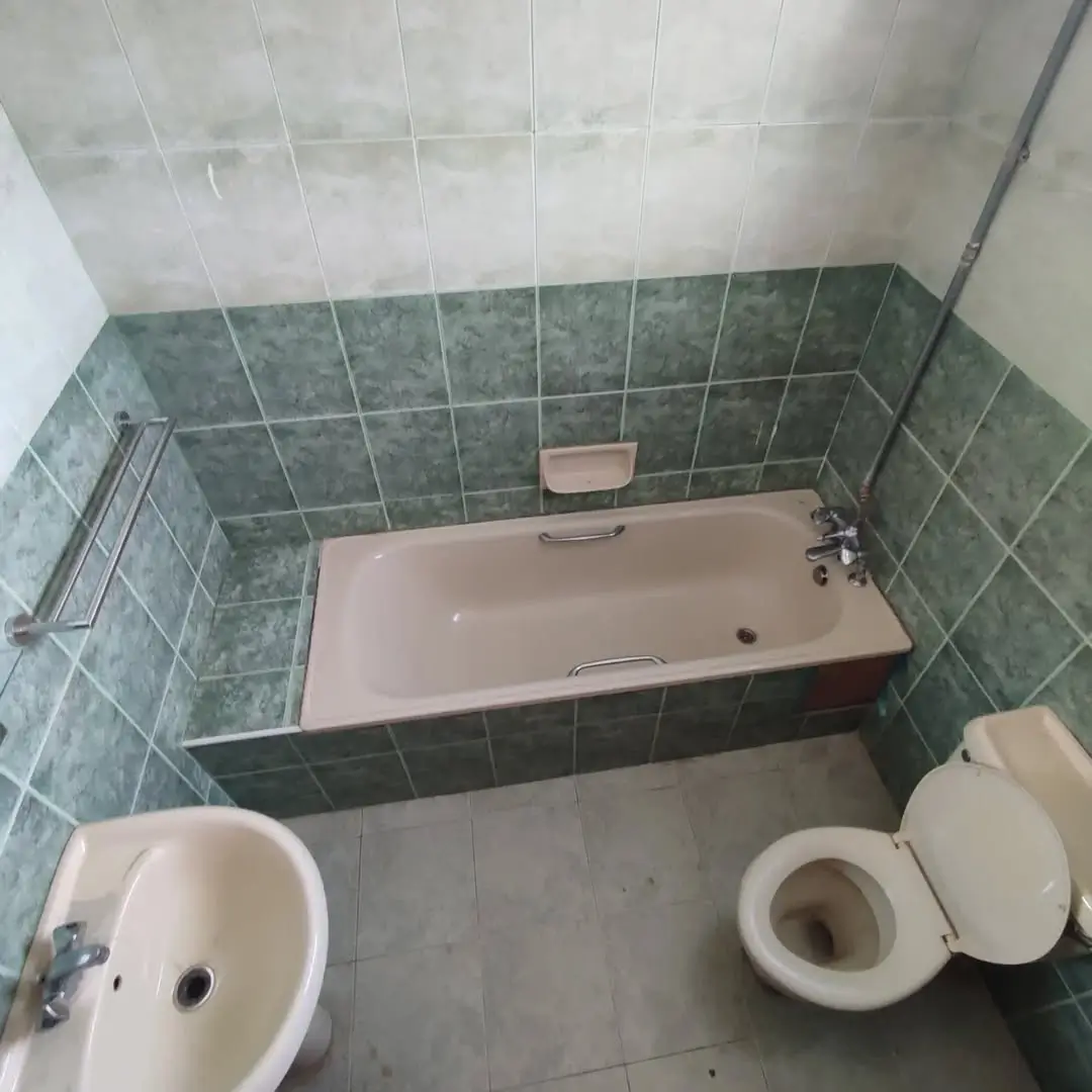 Bathroom with green tile walls, bathtub, and toilet fixture