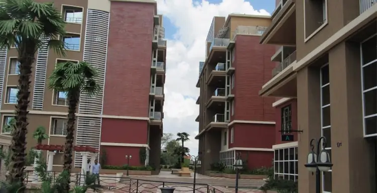Modern residential complex with red brick facades and palm trees