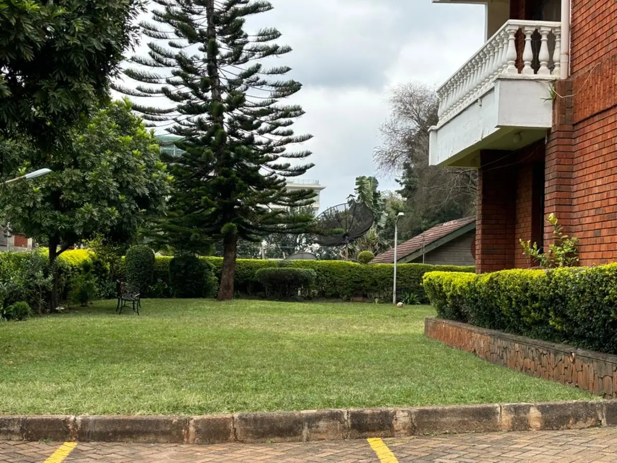 Spacious manicured lawn with mature trees and hedges
