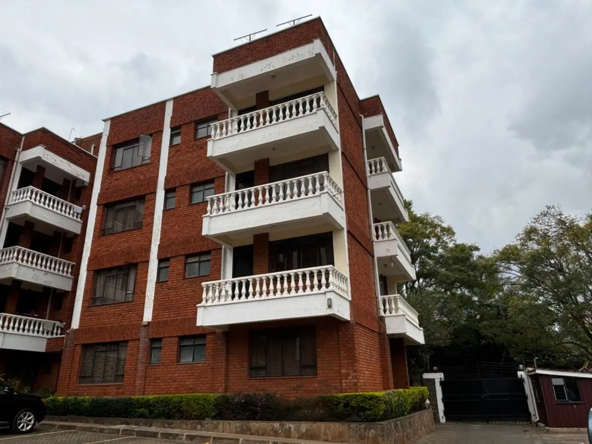 Red brick apartment building with white balconies and landscaping