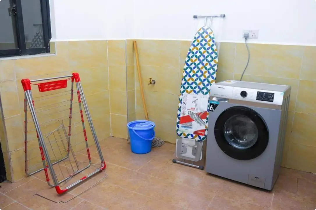 Laundry room with washing machine, drying rack, ironing board