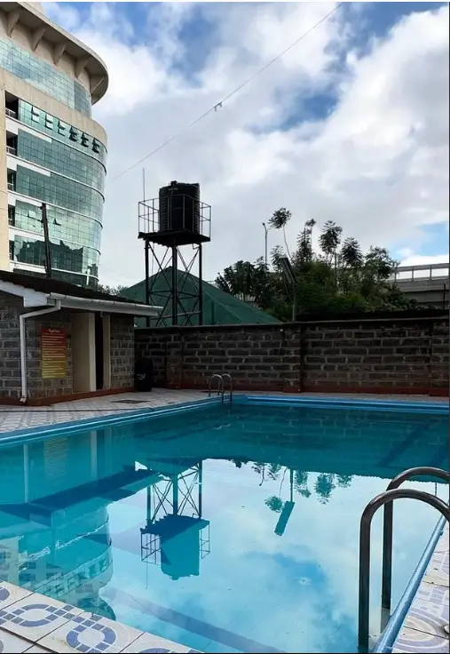 Rectangular swimming pool with surrounding deck and building backdrop