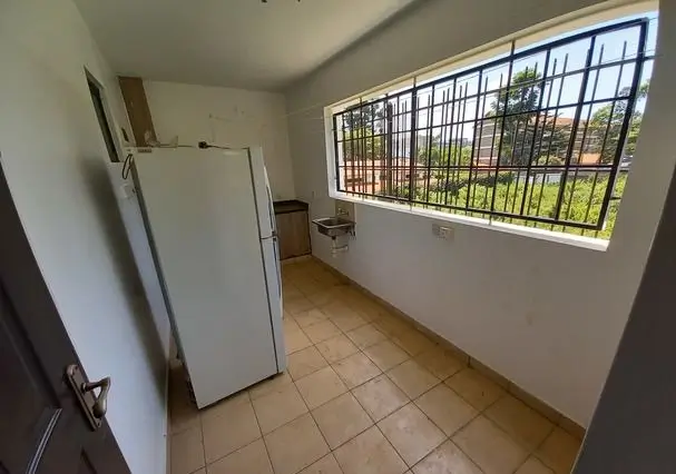 Compact kitchen with refrigerator and barred window view