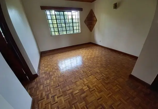 Spacious bedroom with herringbone wood flooring and natural light
