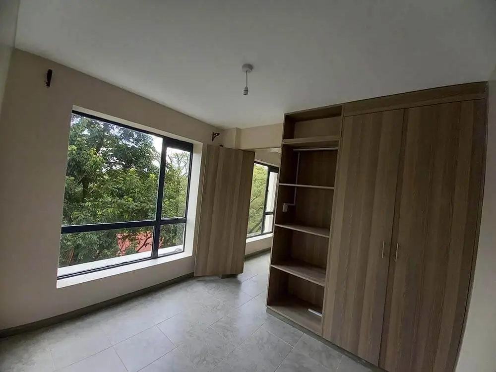 Spacious bedroom with built-in wooden wardrobes and garden view