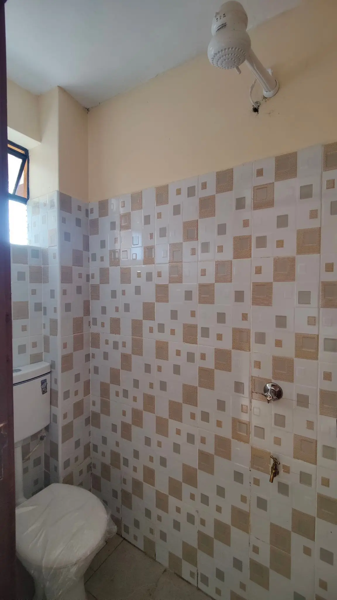 Compact bathroom with checkered tile walls and overhead shower