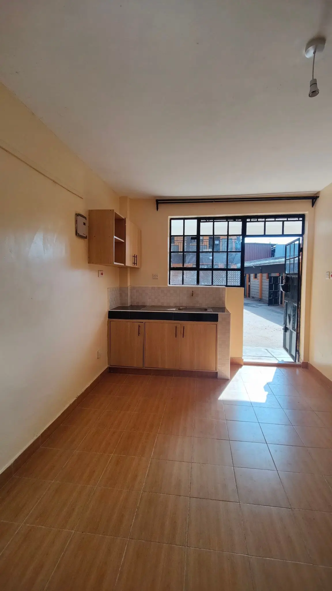 Compact kitchen with wooden cabinets, opening to balcony