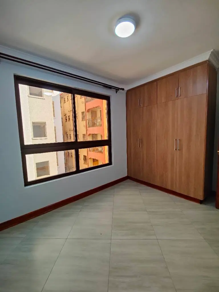 Spacious bedroom with wooden wardrobe and large window