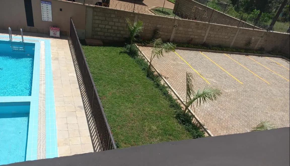 Manicured lawn with paved parking area and pool edge