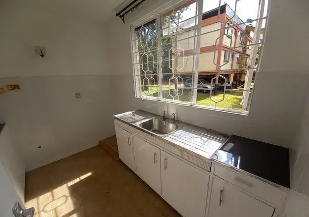Compact kitchen with sink, cabinetry, and barred window