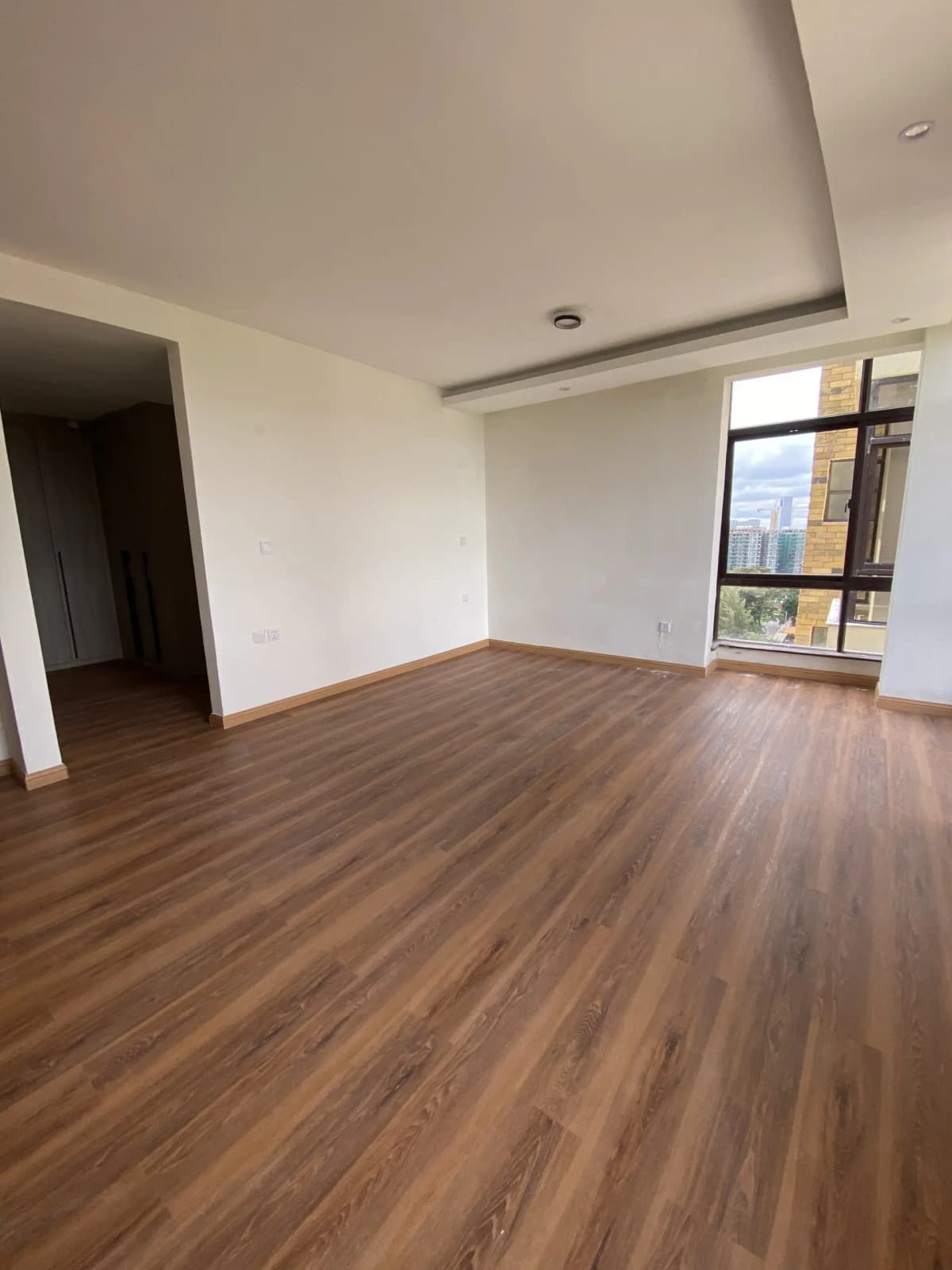 Spacious empty living room with wooden flooring and city view