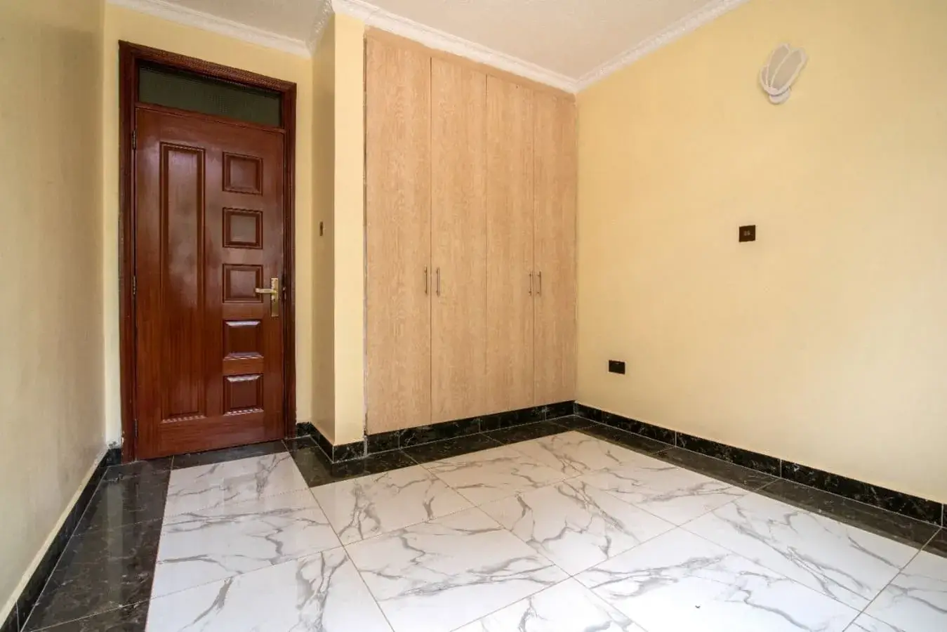 Unfurnished bedroom with marble flooring and wooden wardrobe
