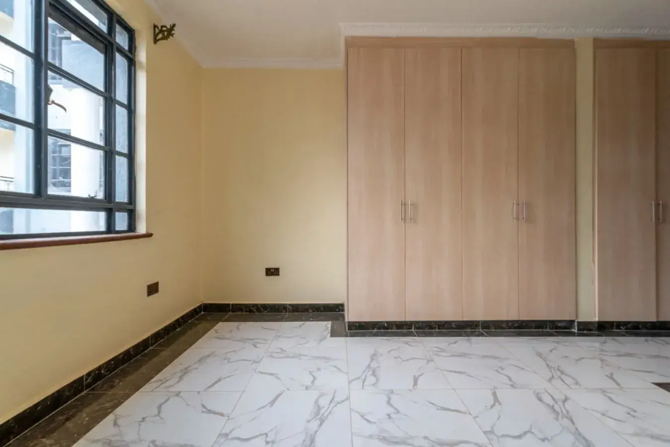 Spacious bedroom with marble flooring and built-in wardrobes
