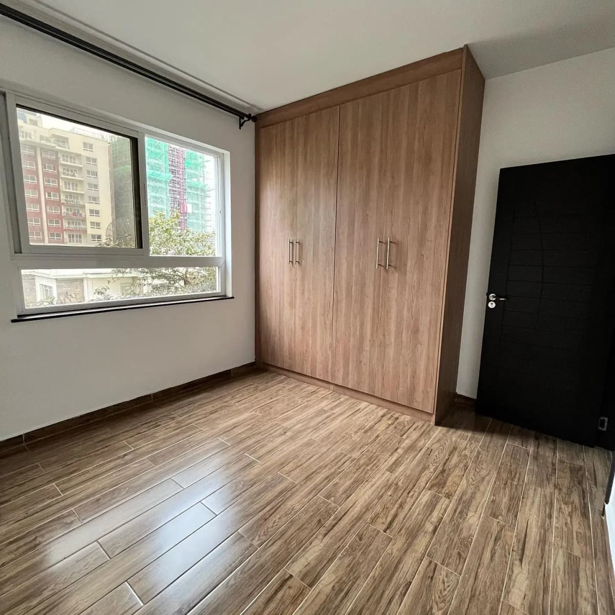 Spacious bedroom with wooden wardrobe and city views