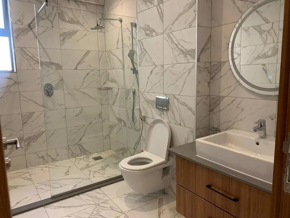 Modern bathroom with marble tiles, walk-in shower, toilet and sink