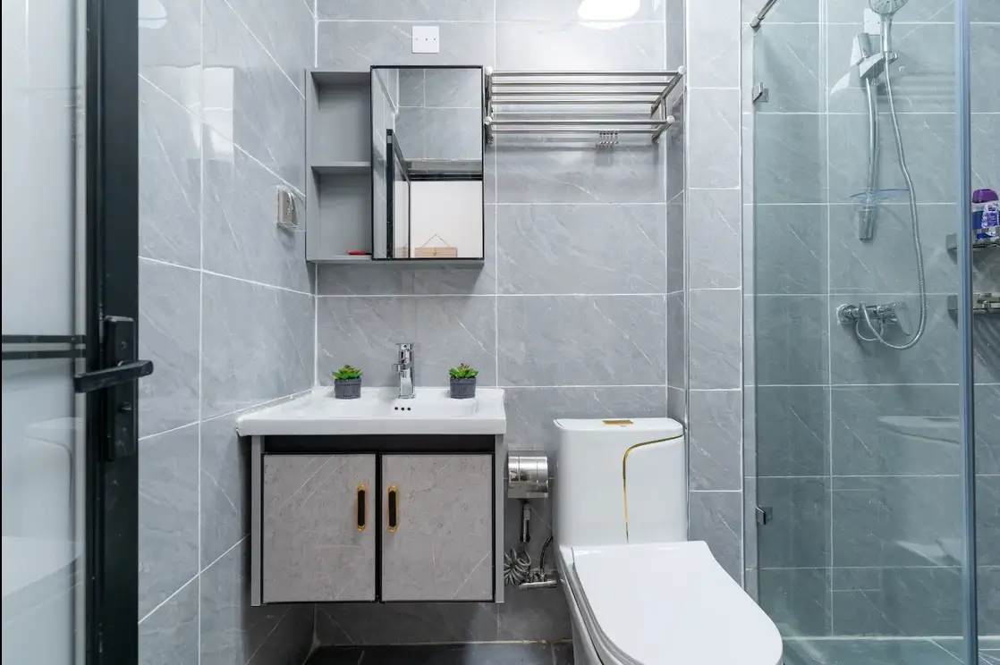 Modern bathroom with marble tiles, vanity sink, and glass shower enclosure