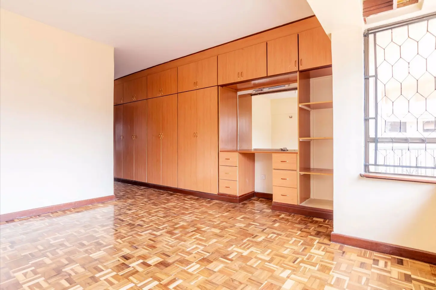Spacious bedroom with built-in wooden wardrobes and shelving