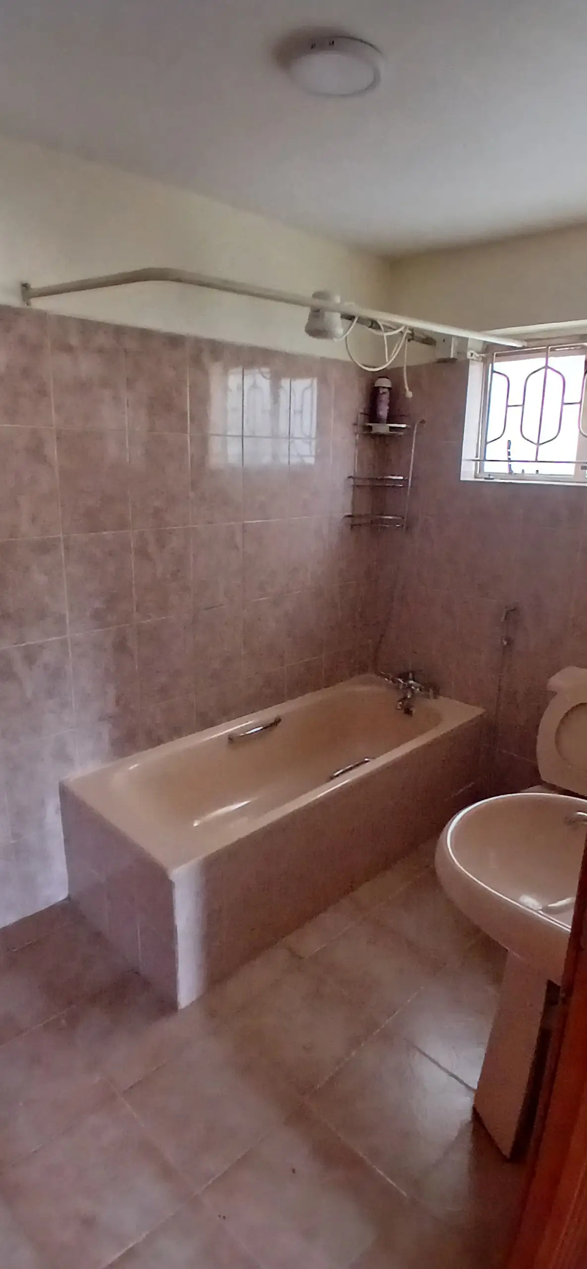 Bathroom with bathtub, shower curtain rod, toilet, pink tiling