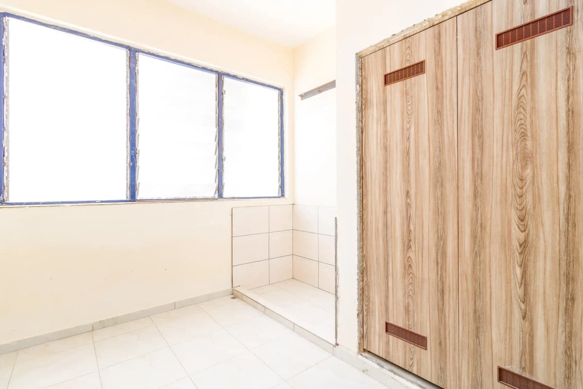 Unfurnished bedroom with large window and wooden wardrobe