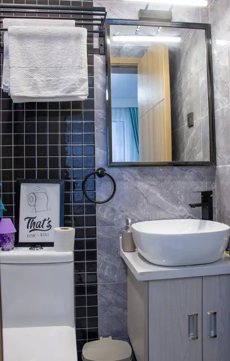 Modern bathroom with black tile walls, round white basin sink